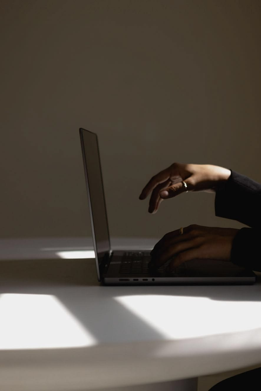 Manos trabajando sobre una laptop en luz baja